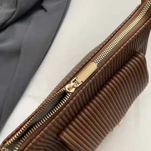 Dettaglio della cerniera dorata e della trama a pieghe marrone sulla borsa elegante