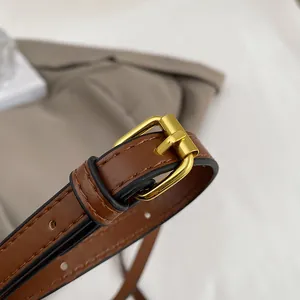 Detail of adjustable brown leather strap with polished gold metal buckle for luxury handbag