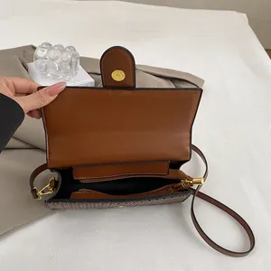 Interior view of brown leather bag showing black lining, zip pocket and golden magnetic clasp