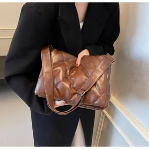 Détail de la texture matelassée douce sur le sac à bandoulière en similicuir marron