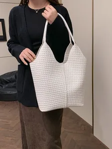 Minimalist white woven tote bag with wide leather handle and textured hobo design