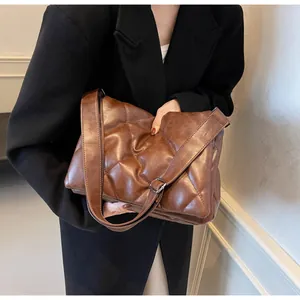 Détail d'un sac bandoulière matelassé marron foncé avec texture rembourrée et large sangle