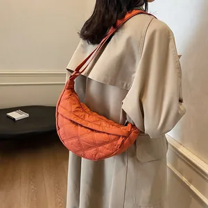 Detail view of the orange quilted crescent bag showing stitching and wide strap