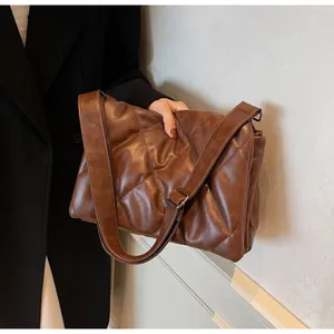 Détail du sac bandoulière matelassé marron foncé avec large sangle et boucle en métal argenté