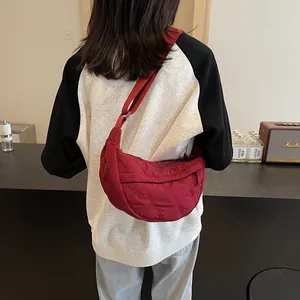 Detailed back view of a burgundy quilted nylon hobo bag carried by a model