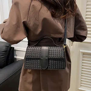 Detailed close-up of premium black woven texture and gold hardware on evening handbag
