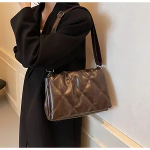 Détail du sac bandoulière matelassé marron foncé avec large sangle sur un modèle