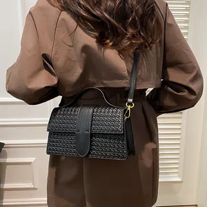 Macro shot of black woven texture leather bag with elegant gold metal buckles and crossbody strap