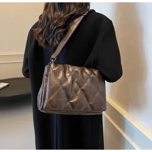 Gros plan d'un sac bandoulière matelassé marron foncé avec une large sangle réglable