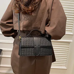 Detailed close-up of woven leather texture on a black evening handbag with gold hardware