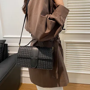 Detail of black woven texture and leather strap on a chic crossbody evening bag