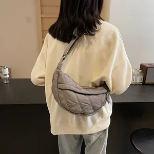 Detailed view of grey quilted crescent shoulder bag with adjustable strap worn by model