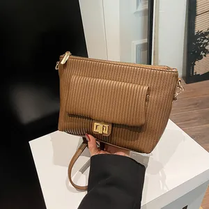 Dettaglio borsa marrone in ecopelle goffrata con strisce verticali e chiusura dorata