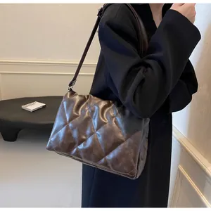 Détail du sac bandoulière matelassé marron foncé porté avec un manteau en laine noir