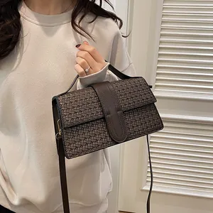 Close-up of dark brown woven leather handbag with top handle and vertical strap detail