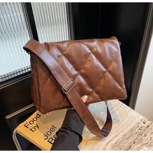 Détail d'un sac à bandoulière matelassé marron avec large sangle et boucle métallique