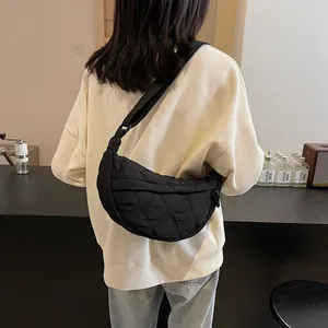 Detail of black quilted half-moon bag featuring classic rhombus pattern and wide strap
