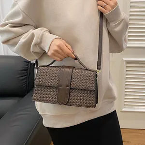 Detail of dark brown woven texture handbag with gold hardware and fine PU leather craftsmanship