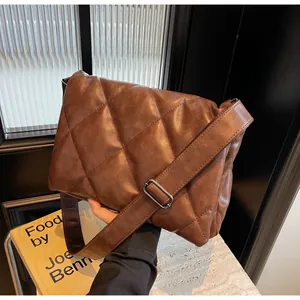 Gros plan d'un sac bandoulière matelassé marron avec large bandoulière et boucle en métal