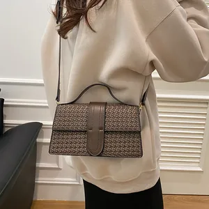 Detailed view of dark brown woven texture handbag shown with shoulder strap on a model