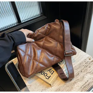 Gros plan du sac bandoulière matelassé marron avec bandoulière réglable sur marbre