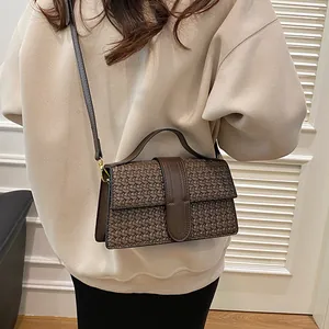 Close-up of brown woven texture handbag with top handle and vintage buckle strap