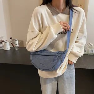 Close-up of blue quilted half-moon bag with adjustable shoulder strap on female model