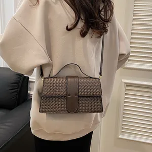 Detail of dark brown woven leather handbag with smooth strap and crossbody versatility