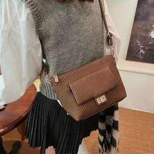 Dettaglio borsa a tracolla marrone a pieghe con chiusura a scatto dorata su modella