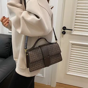 Close-up of dark brown woven texture handbag with rectangular flap and top handle