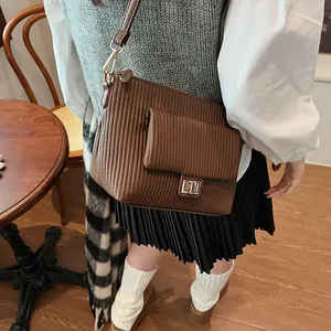 Dettaglio borsa a tracolla vintage marrone con trama a pieghe e chiusura dorata