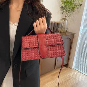 Close-up of elegant red woven texture handbag paired with a stylish black suit jacket