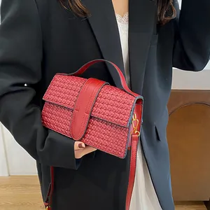 Detail of red woven texture evening bag with golden metal hooks and leather strap