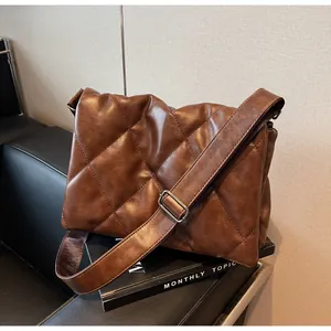 Détail du sac bandoulière marron foncé matelassé avec coutures à grands carreaux