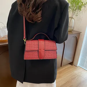 Detail of wine red woven leather texture on a stylish handbag with gold metal hooks