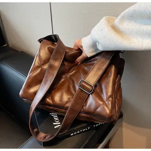 Détail du sac à bandoulière matelassé marron foncé avec sangle large réglable et boucle en métal