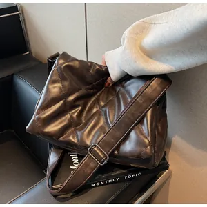 Détail du sac à bandoulière matelassé marron foncé avec large sangle et cuir synthétique
