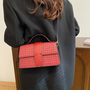Detail of red woven evening bag with gold metal clasp shown on a model