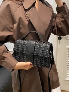 Elegant black woven texture handbag for women held by model in stylish trench coat