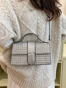 Silver woven evening crossbody bag with top handle shown on a white knitted sweater