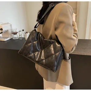 Détail du sac bandoulière noir matelassé avec sangle réglable et finition brillante