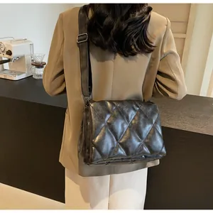 Détail d'un sac bandoulière matelassé noir avec une large sangle en cuir et boucle en métal