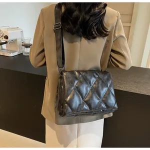 Détail du sac à bandoulière matelassé noir porté avec un blazer dans un café chic