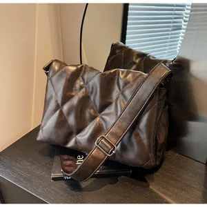 Détail d'un sac bandoulière matelassé marron foncé en cuir souple avec boucle argentée