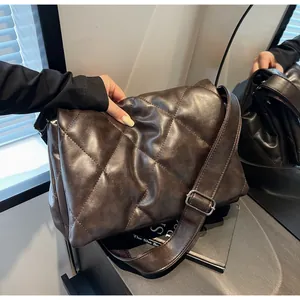 Détail d'un sac bandoulière matelassé marron foncé avec texture souple et boucle argentée