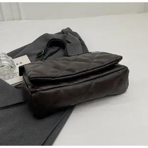 Détail d'un sac bandoulière marron foncé matelassé avec une bandoulière réglable