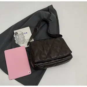 Détail du sac bandoulière matelassé marron foncé sur costume avec tablette incluse