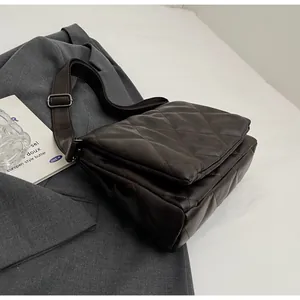 Détail d'un sac bandoulière matelassé marron foncé avec large bandoulière réglable