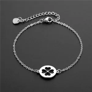 Bracelet en acier inoxydable argenté avec un pendentif trèfle évidé sur fond noir élégant