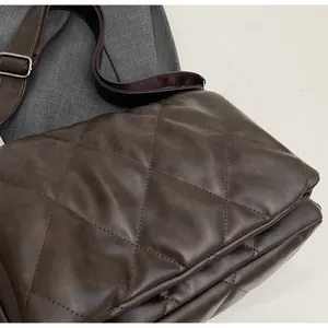 Gros plan d'un sac bandoulière marron foncé matelassé avec sangle réglable et boucle argent
